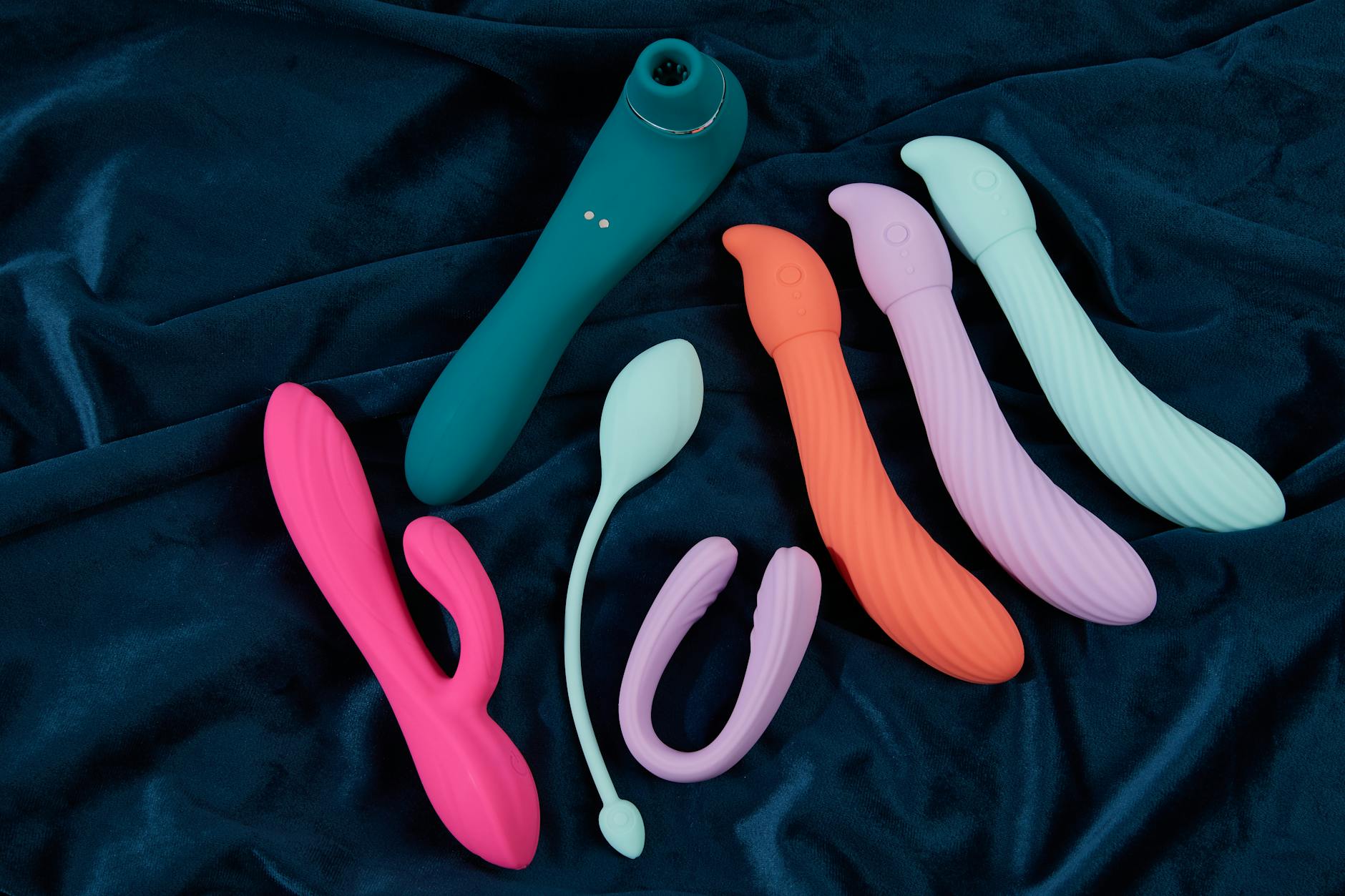 Three colorful clitoral vibrators arranged on white fabric, highlighting their smooth texture.