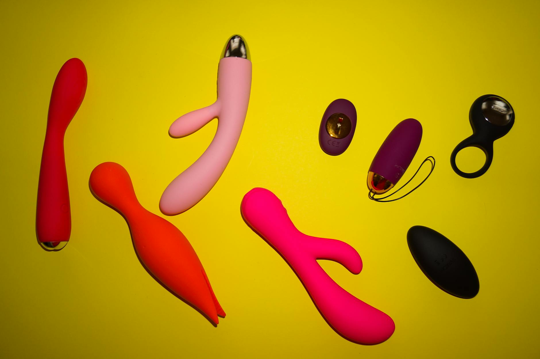 Vibrant photo of various sex toys arranged on a bright yellow surface