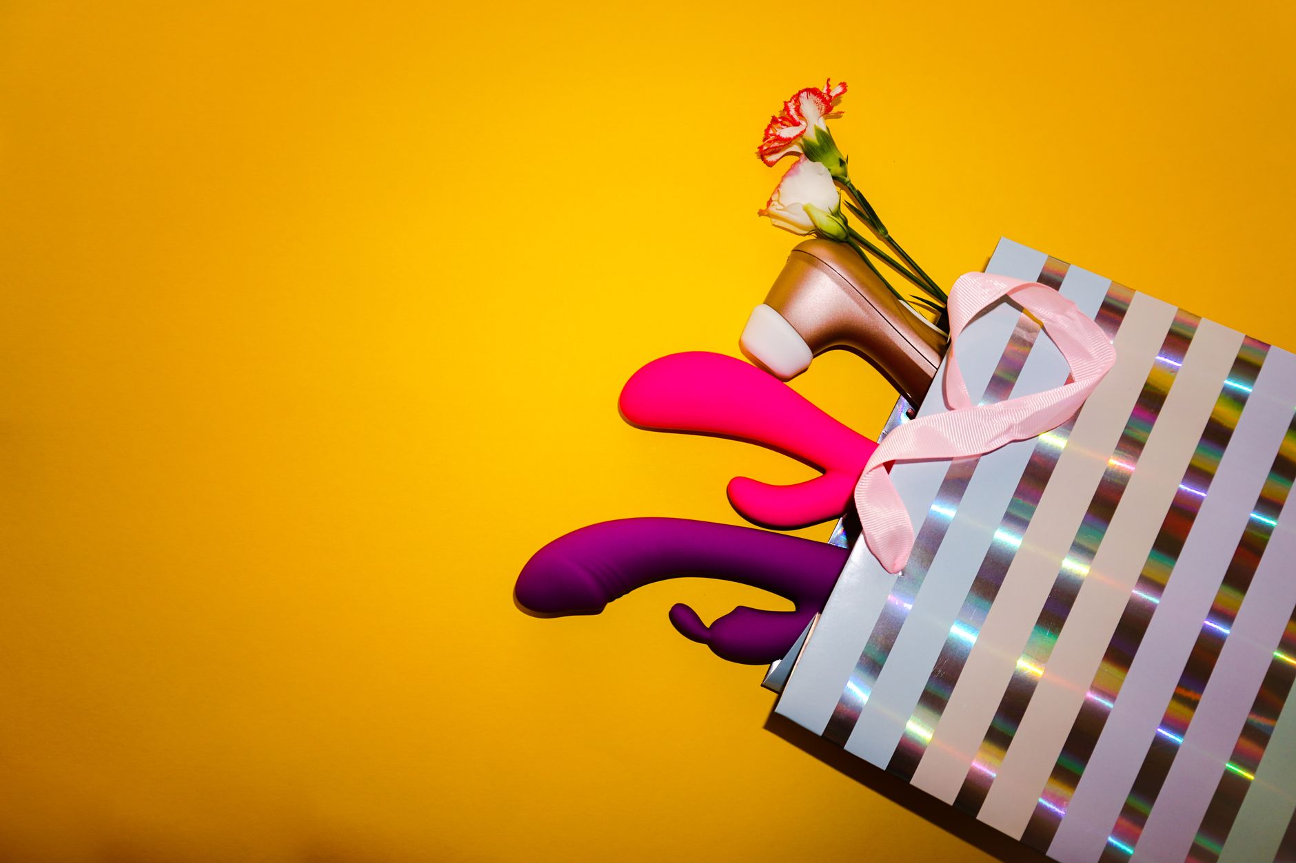 Close-up of a blue clitoral vibrator held in hand against a purple background