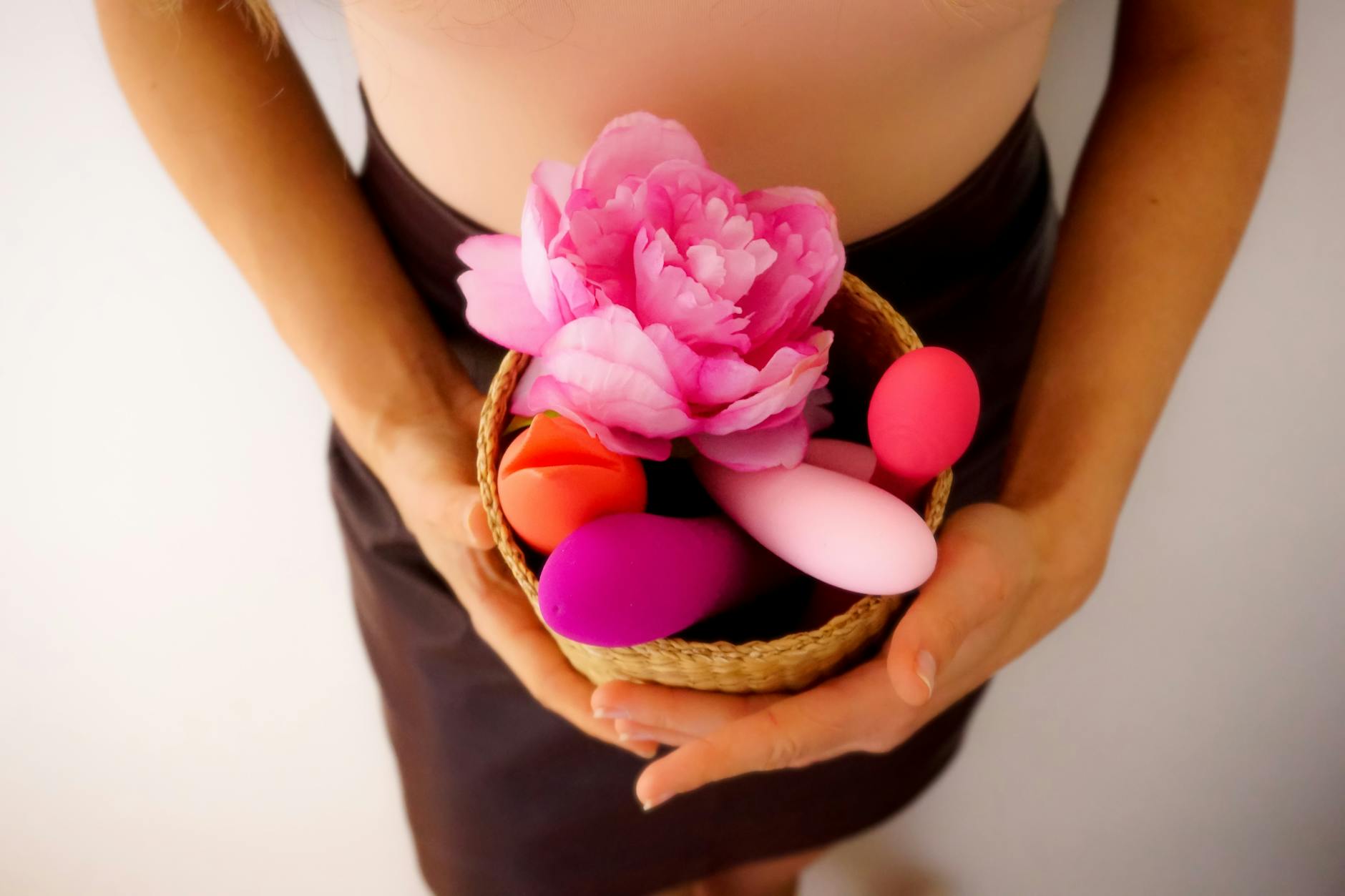 Woman holding a pink vibrator with intimacy and personal wellness books nearby