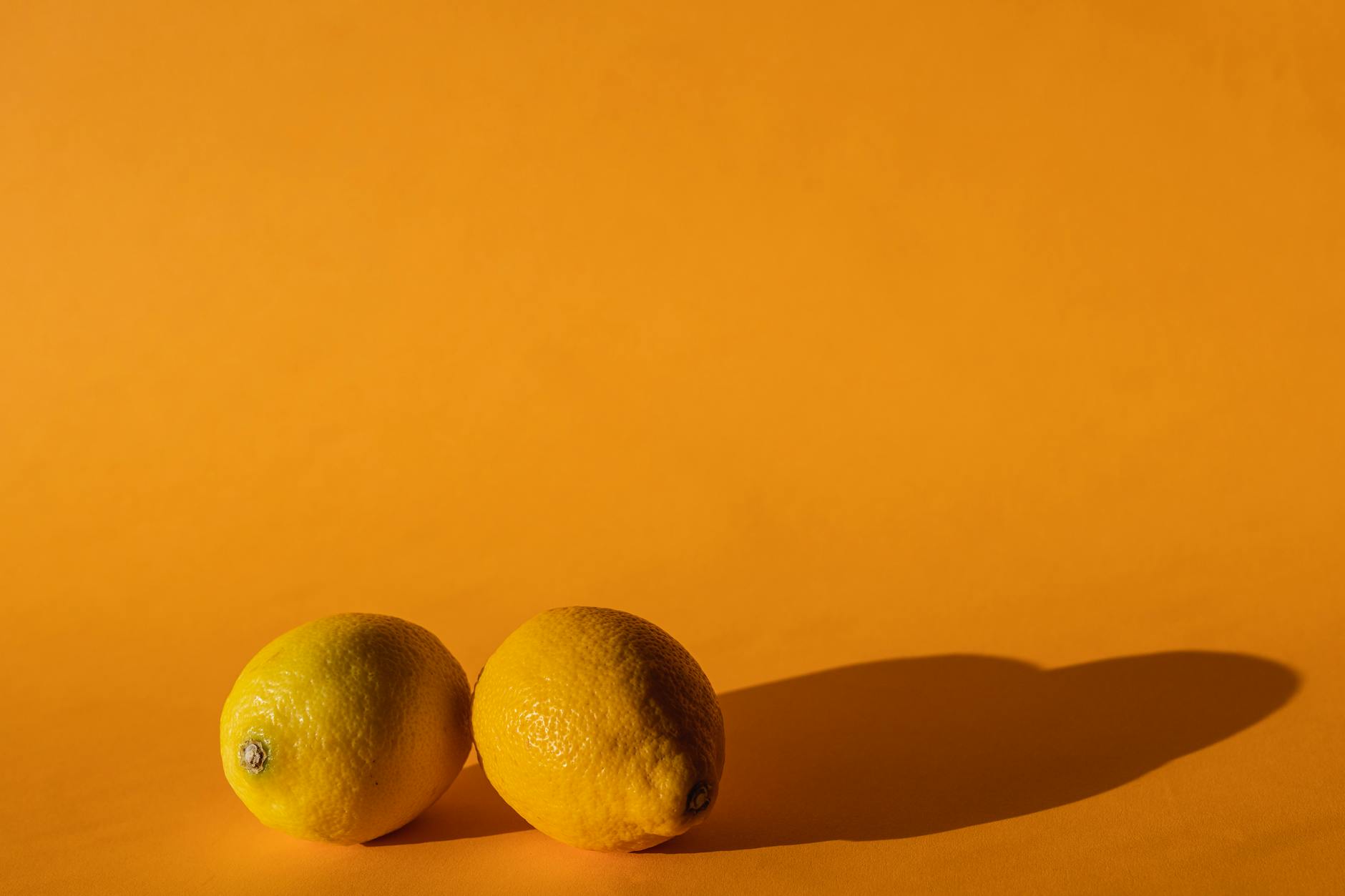 Two women smiling together with lemon slices, expressing joy and comfort indoors